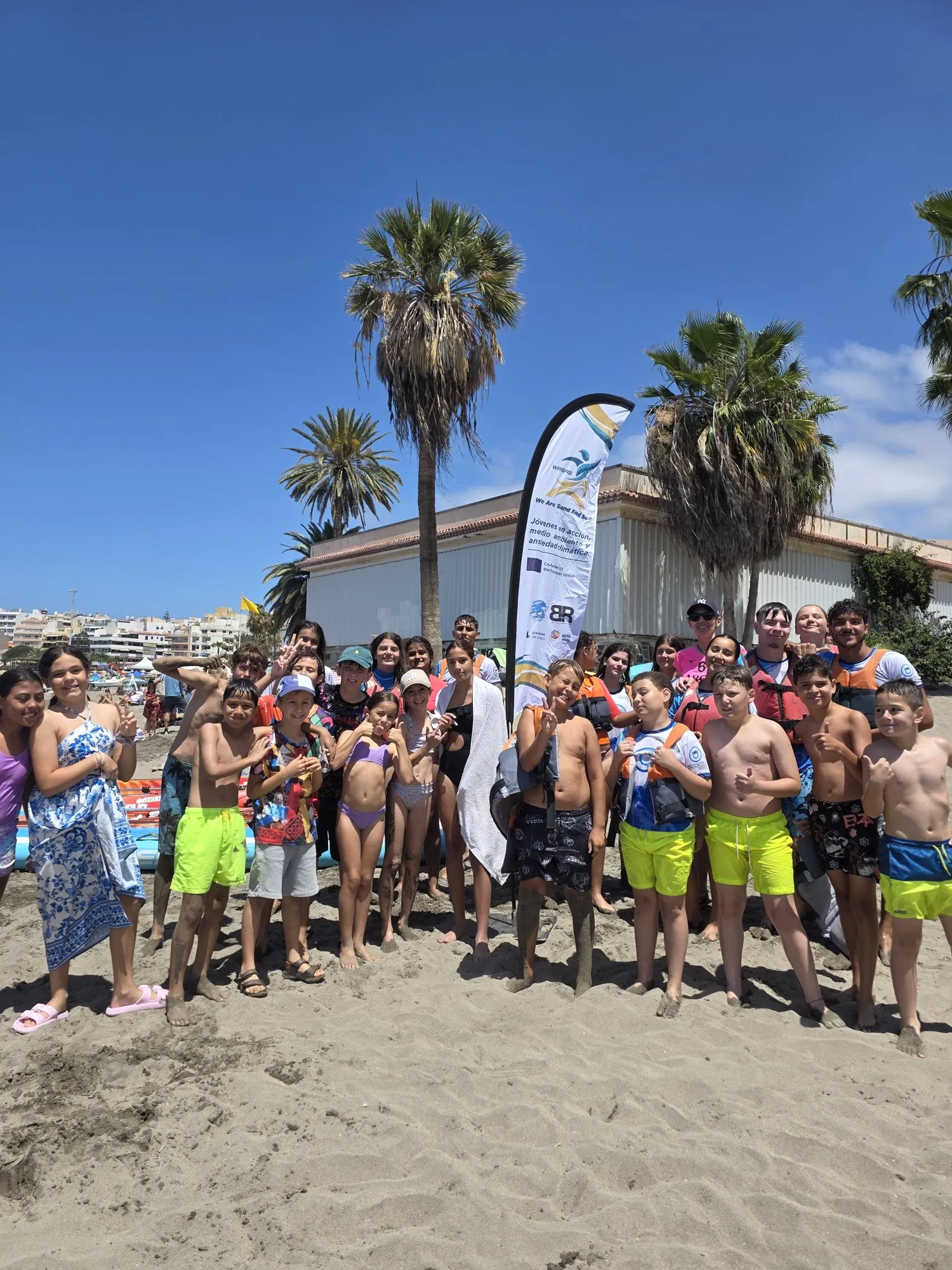 Young WASAS participants gathered on the beach beside the project banner