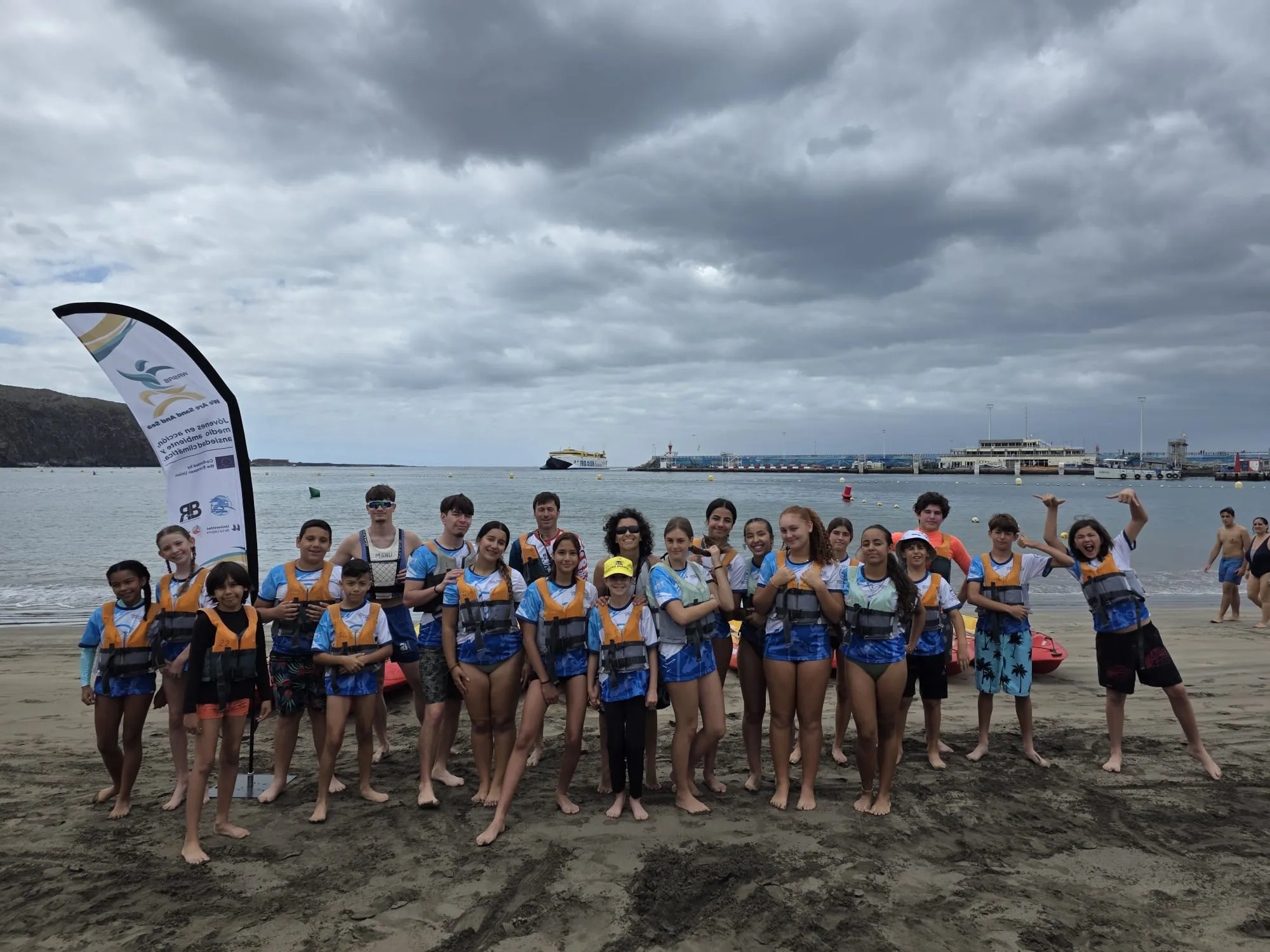 Participants in life jackets gathered on the beach at the end of the session