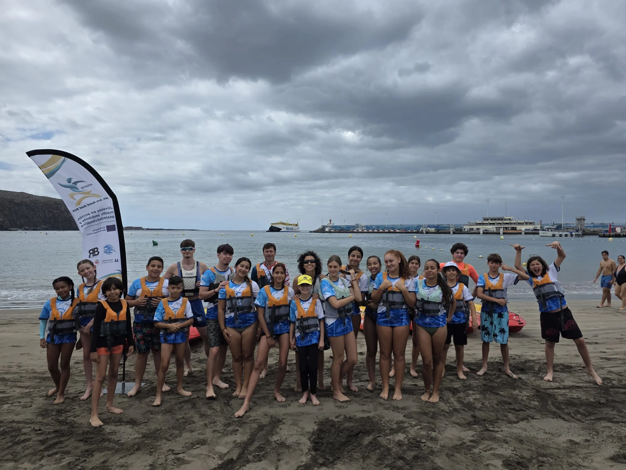 Participants in life jackets gathered on the beach at the end of the session