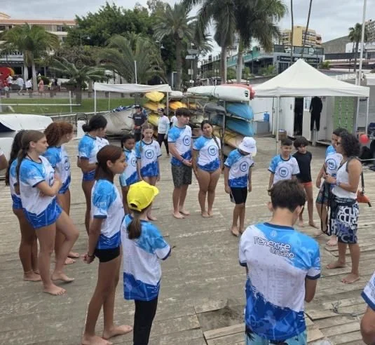 Young participants in life jackets receiving instructions beside the kayaks