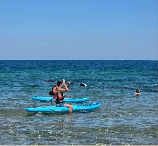 A participant paddling on a paddleboard in turquoise water