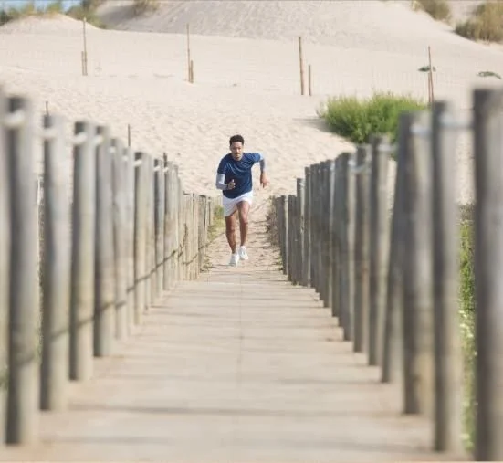 A runner on a wooden boardwalk between the dunes