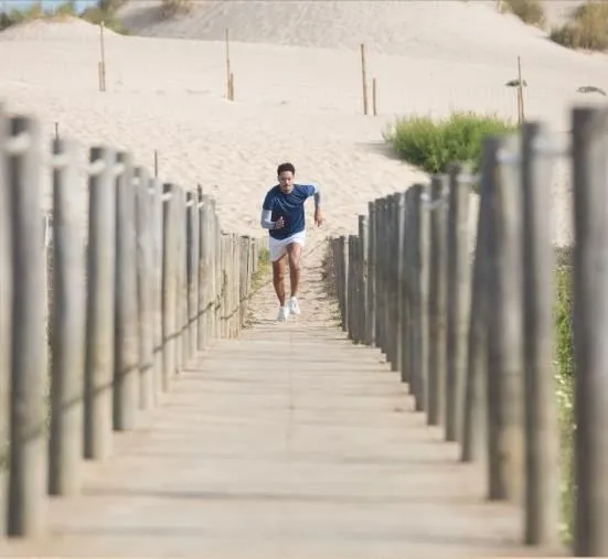 A runner on a wooden boardwalk between the dunes
