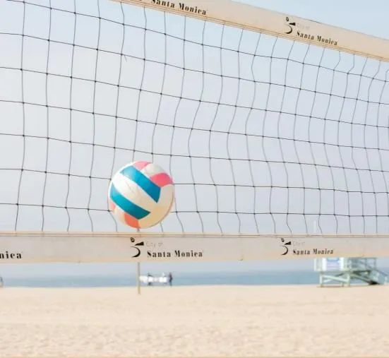 A volleyball above the net on a beach court