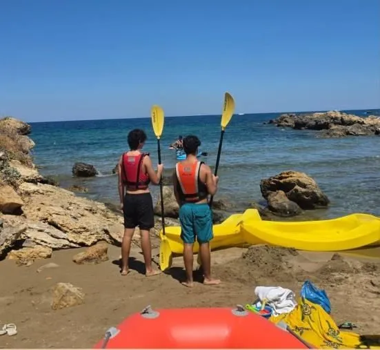 Two participants in life jackets standing beside yellow kayaks by the sea